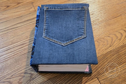 Finished reading journal bound in denim with a front jeans pocket, closed on an oak floor.